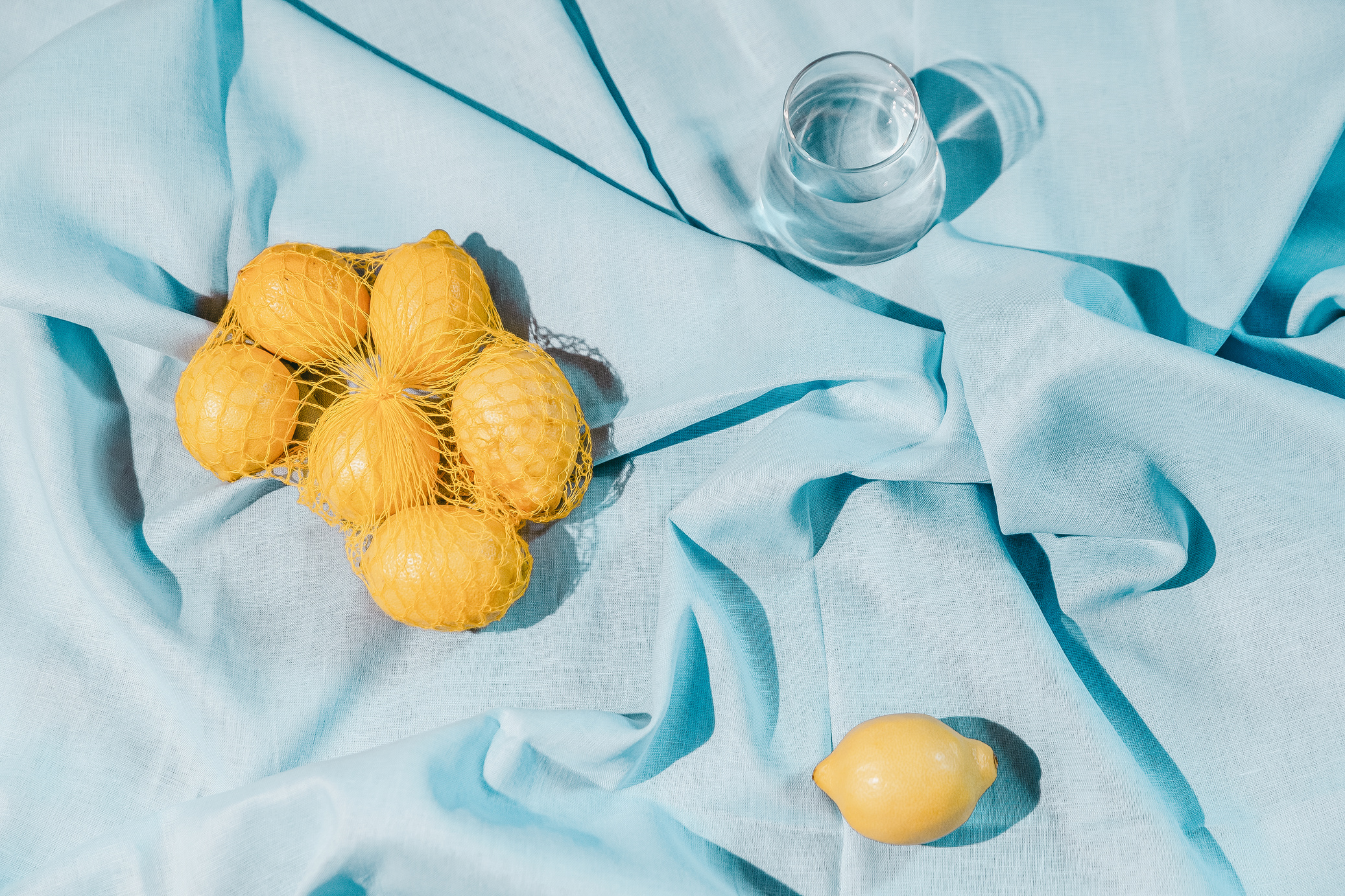 Lemon Fruits in Net with Glass of Water 